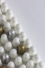 Playful Concepts: Gold, Silver and Bronze game pieces in a crowd of white pieces
