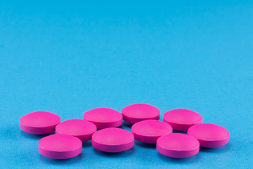 close up of pink round pills on blue background