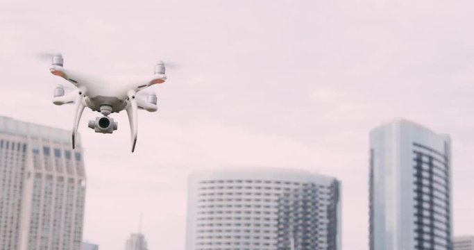 Quadcopter drone with camera on gimbal flying in the city sky, shot in slow motion 