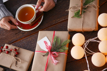 Woman sitting on the desk with christmas gift box. Hands of woman