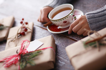 Woman sitting on the desk with christmas gift box. Hands of woman