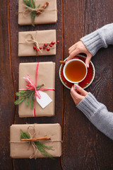 Woman sitting on the desk with christmas gift box. Hands of woman