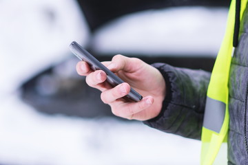 Man holding mobile phone and calling winter car services to help. - obrazy, fototapety, plakaty