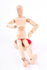 Wooden dummy sitting on white background. Human wooden mannequin touching its stomach. Wooden dummy sitting over white.