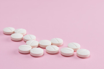 small white round pills on pink background