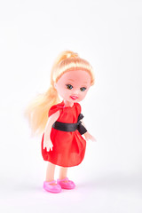 Smiling baby doll on white background. Little doll with beautiful smile in red dress standing on white background. Cute doll with positive emotions.