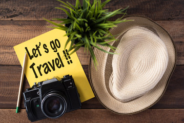 wanderlust - travel concept.camera,hat,pencil and note "let's go travel" on wooden background