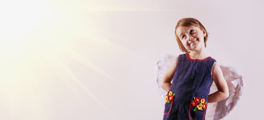 Child girl with angel wings in sun rays as symbol of goodness, security, protection and happy childhood