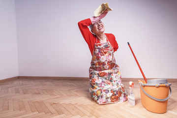 Stressed and lonely old cleaning lady in pain while working