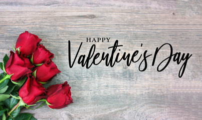 Fototapeta na wymiar Happy Valentine's Day Text with Holiday Rose Bouquet in Corner Over Rustic Wooden Background