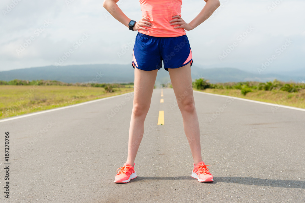 Wall mural female marathon runner standing on country road