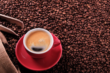 Red coffee cup and saucer one single for espresso or capuccino on a background of scattered dark coffee beans photo
