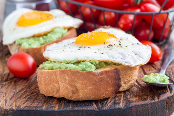 Fototapeta na wymiar Open sandwiches with mashed avocado and fried egg on bread, horizontal