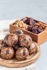 Healthy homemade energy balls with cranberries, nuts, dates and rolled oats on a wooden plate, vertical, copy space