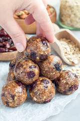 Healthy homemade energy balls with cranberries, nuts, dates and rolled oats on parchment, vertical
