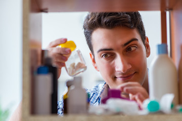 Sick ill man looking for medicines at farmacy shelf