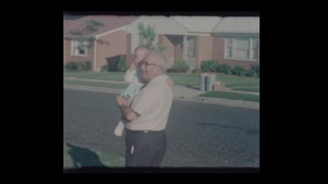 1964 Proud Grandfather carries baby granddaughter