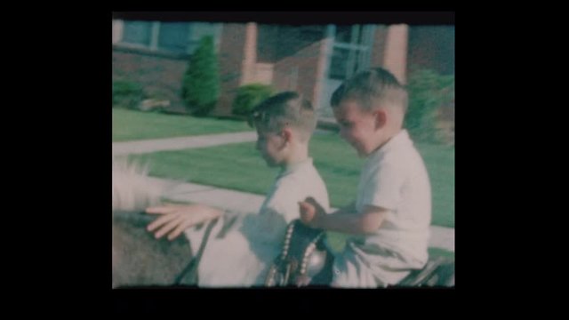 1964 Little boys ride pony on suburban street with antique cars