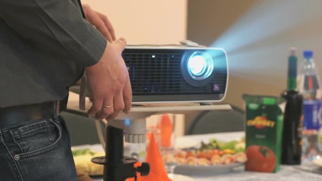 Close-up of unknown man adjusting white projector in the celebration anniversary