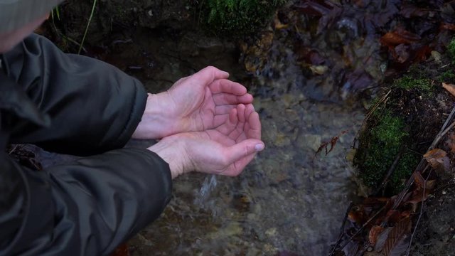 Man takes handful of mountain water - (4K)