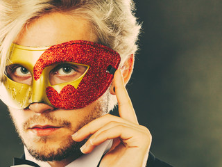 Young man in carnival mask on dark
