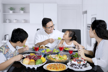 Young father feeding his daughter in the kitchen