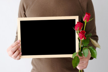 Valentines' day background, Man hand holding red roses and blank chalkboard standing over white background