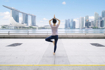 Fototapeta na wymiar Asian woman meditating in the esplanade bridge