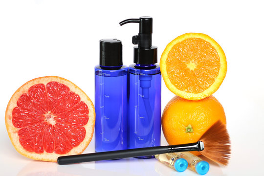 AHA fruit acids. Pilling fruit acids for the face in blue bottles, cosmetic brush, ampoule with serum and citrus fruits on white background. facial peeling with  fruit acids.  beauty concept