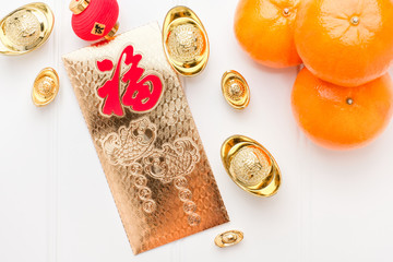 Top view Chinese New year golden envelope packet ( ang pow ) with gold ingots and tangerine on...