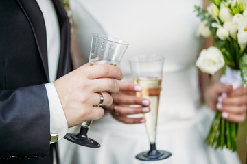 The groom holds a glass of champagne next to the bride