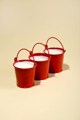 Three red buckets with milk on a yellow background