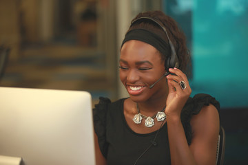 Smiling woman in headset working on computer