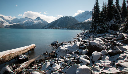 Fototapeta na wymiar Peaceful Garibaldi Lake with snow covered rocks at the shore