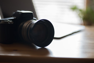 Fototapeta na wymiar Eine Analoge Spiegelreflex Kamera und ein Laptop auf einem Tisch im Büro