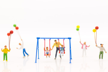Miniature people : father swing cradle with children, and childrens play balloon together wiht fun, using as background International day of families concept.