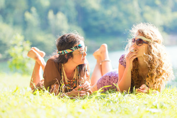 Pretty free hippie girls laying on the grass - Vintage effect photo - obrazy, fototapety, plakaty