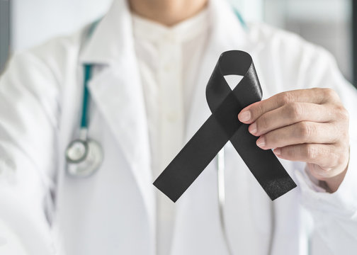 Black ribbon awareness in doctor's hand for Melanoma and skin cancer, Narcolepsy, Primary Biliary Cirrhosis (Cholangitis), Sleep Apnea Disorders
