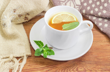 Tea with lemon and mint beside of woolen mittens, scarf