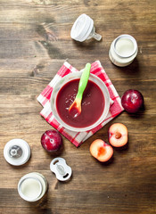 Baby food. Puree from fresh plums with baby milk in a bottle.
