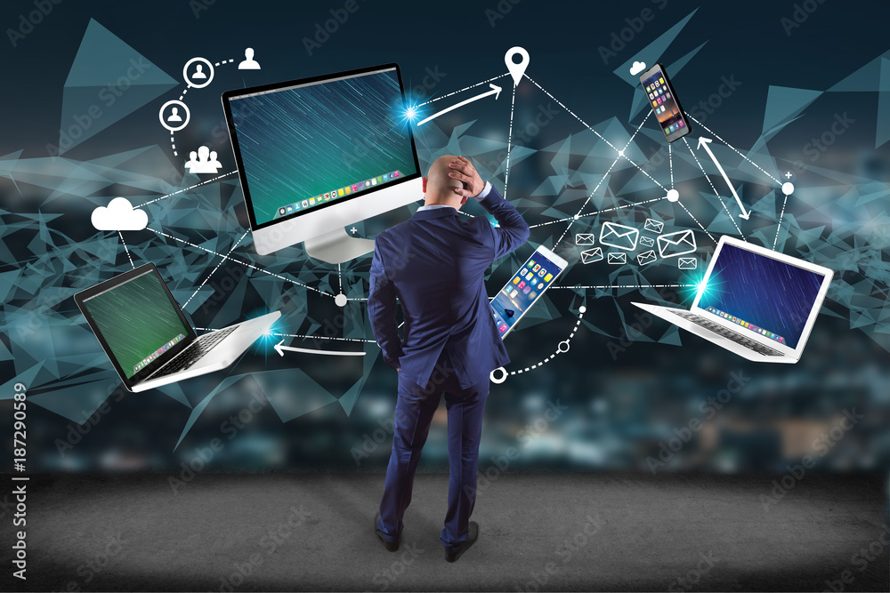 Poster businessman in front of a wall with computer and devices displayed on a futuristic interface with in