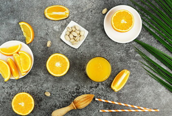 healthy breakfast of freshly squeezed orange juice and pistachio nuts on a light gray table. top view