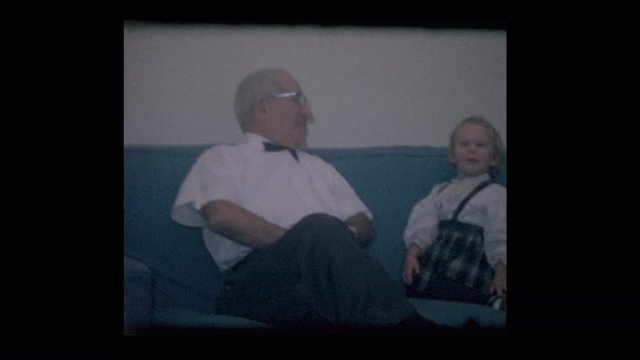 1964 Grandfather hanging with grandchildre on blue sofa