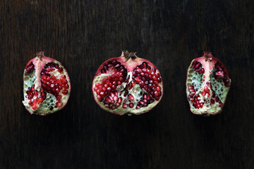 Pomegranate slices on dark wooden table, top view