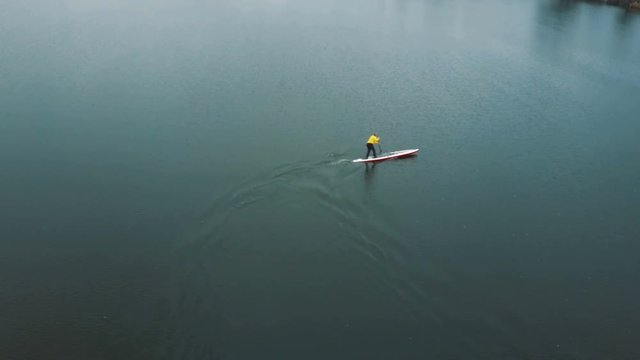 Sup board aerial drone footage. Professional rower performs a turn on a stand up paddling board.