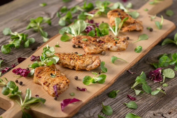 Fresh freshly fried delicious slices of meat on a wooden board with fresh herbs. Appetizing steaks on a wooden board. Still life.