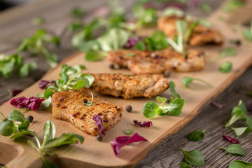 Fresh freshly fried delicious slices of meat on a wooden board with fresh herbs. Appetizing steaks on a wooden board. Still life.