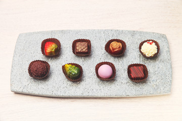 Chocolate candies of different shapes on gray slate plate 
