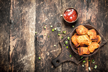 Chicken nuggets in a bowl with tomato sauce.