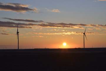 日の出と風力発電の風車